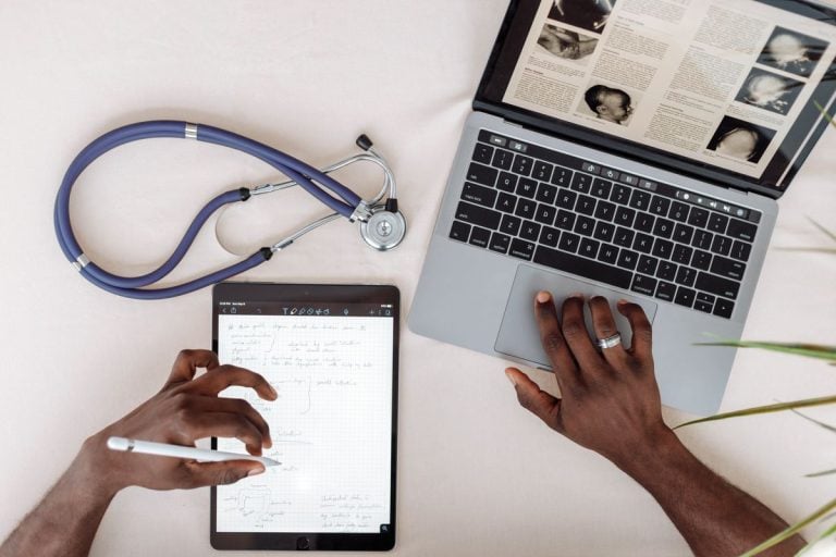 Locum GP appraisal preparation: stethoscope, laptop and handwritten learning notes on a desk